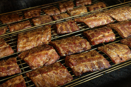 Grilled barbecue pork ribs in a smoker at the factory. The concept of a delicious snack for a picnic or a country house.の写真素材