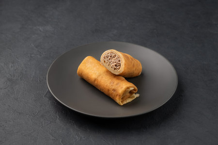 Delicious crepes roll with meat chicken on a plate on a dark  isolated background. Concept of...