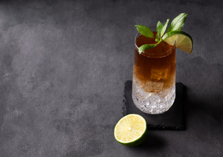 Coffee brew with tonic, ice and lime in a tall glass on a dark background. Concept craft refreshing...