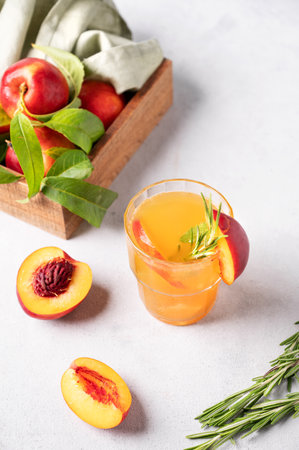 Refreshing peach tea with ice and rosemary. Homemade cold healthy vegetarian drink on a light  background with fresh fruits and herbs. Top view.の写真素材