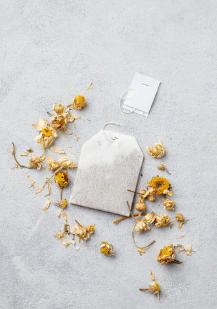 Dried chamomile in a tea bag on a light background. Healthy food and drink concept. Herbal  and alternative medicine with dry herbs. Top view and copy space.の写真素材