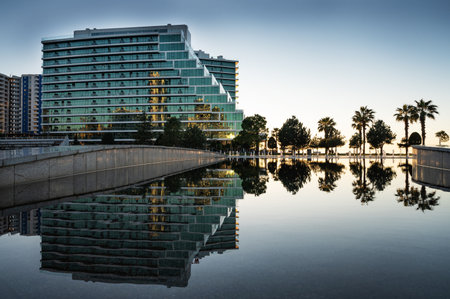 View of a modern beautiful building with glass balconies with a lake in the foreground. Urban architecture concept at sunset. Batumi, Georgia.の写真素材