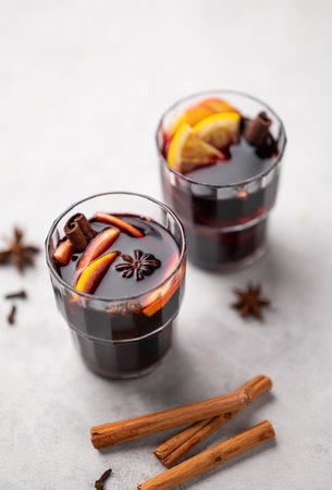 Mulled wine with orange, apple and cinnamon in glasses on a light background. The concept of a traditional winter hot drink with spices and fruits. Top view and copy space.の写真素材