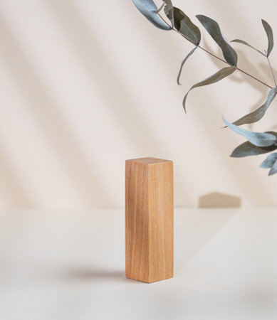 Abstract empty wooden podium with shadows and leaves on a beige background. Layout concept for promotional product presentation, sale or cosmetics display. Front view and copy space.の写真素材