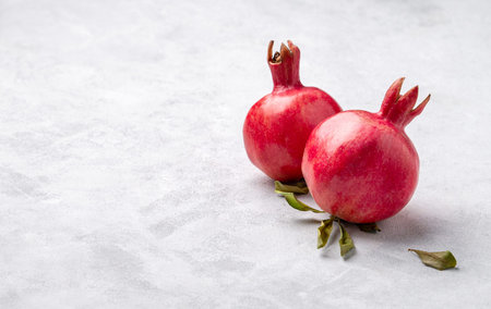Ripe red pomegranate fruits with leaves on a light texture background. The concept of natural and...