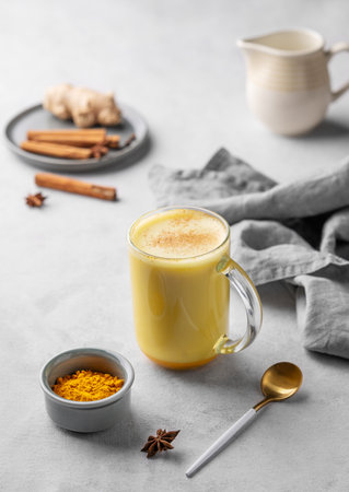 Turmeric golden milk latte with spices and honey. Detox, immunity boosting, anti-inflammatory, healthy, cozy drink in a glass cup on a light background.の写真素材