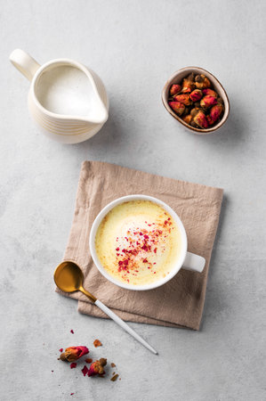 Flat lay of a golden milk latte with turmeric and rose petals. Trendy Indian drink Moon milk with natural spices. Concept of alternative medicine and Ayurveda for immunity. Top view.の写真素材