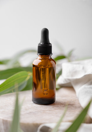 Face and body serum in bottle on a marble background with green leaves. The concept with stage for health and beauty product presentation, sale or cosmetics advertising banner.の写真素材