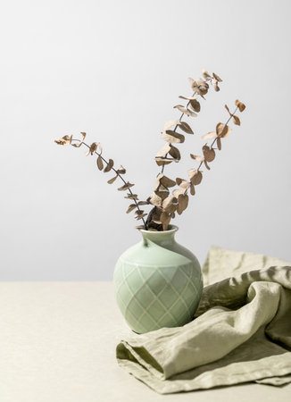 Green vase with dried eucalyptus,  and napkin on a gray background with shadow. Free space for text.の写真素材