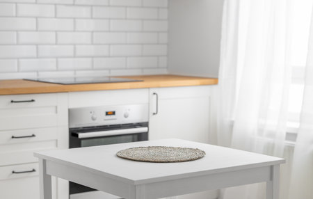 Wooden tabletop with napkin for product montage or mockup against blurred white kitchen with brick wall  in scandinavian style in morning light. Copy space.の写真素材