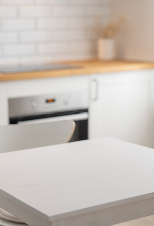 Wooden tabletop with free space for product montage or mockup against blurred white kitchen with brick wall  in scandinavian style in morning light. Copy space.の写真素材