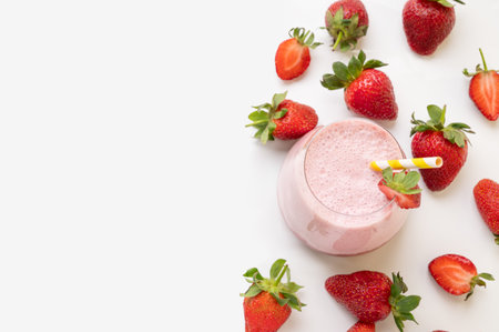 A strawberry milkshake or smoothie in a glass with strawberries on a white background with fresh berries. Healthy food and drink concept. Top view and copy space.の写真素材