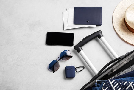 Flat lay suitcase with travel accessories, hat and sunglasses on a light background. Travel concept....