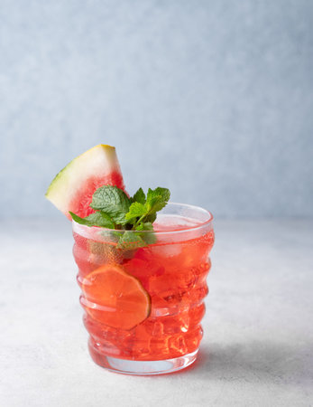 Mojito drink with watermelon, lime, ice and mint in a glass on a light background. Trendy summer refreshing lemonade concept for cocktail menu. Front view and copy space.の写真素材