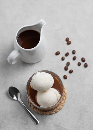 Affogato coffee with vanilla ice cream scoops and  espresso in a glass on a light  background with...