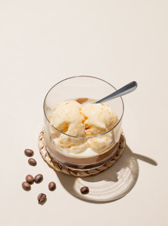 Affogato coffee with vanilla ice cream scoops  and espresso in a glass on a light background with coffee beans, spoon  and shadow. Classic Italian dessert concept. Top view and copy space.の写真素材