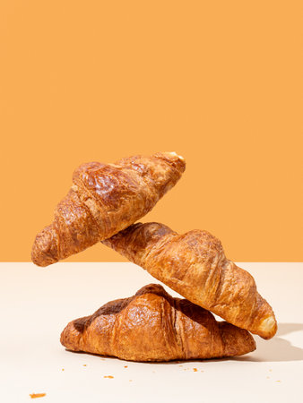 Stack of fresh croissants on yellow and orange background. Creative trendy layout and concept of healthy food or french breakfast. Copy space.の写真素材