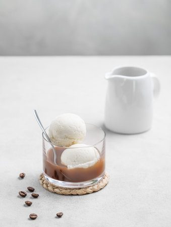 Affogato coffee with vanilla ice cream scoops and  espresso in a glass on a light  background with...