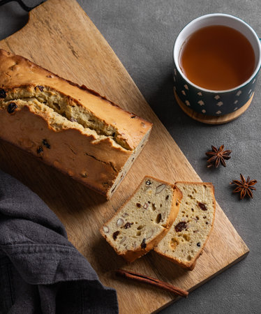 Spicy pie with fruits, nuts and spices on a wooden board, on a dark background with cinnamon and a...