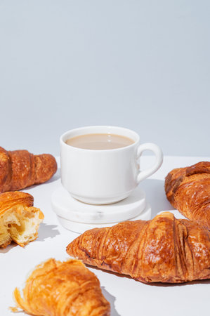 Fresh croissants on a light background with freshly brewed coffee with milk. Creative layout for...