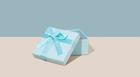 Open blue gift box on beige background. Concept of advertising blank mockup or banner for holiday or greeting card. Free space for text.の写真素材