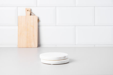 Kitchen countertop with marble stands and wooden board on white brick background. Scandinavian interior concept for product display or advertising. Front view and copy space.の写真素材