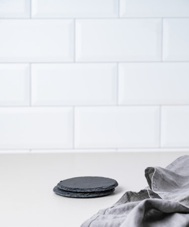 Kitchen countertop with black slate stands and napkin on white brick background. Scandinavian interior concept for product display or advertising. Front view and copy space.の写真素材