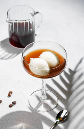 Affogato coffee with vanilla ice cream scoops and espresso in a tall glass on a white background...