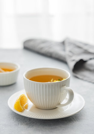 Cup of herbal tea with lemon and honey on table against window background with morning natural light. Concept of healthy vitamin drink for breakfast. Copy space.の写真素材
