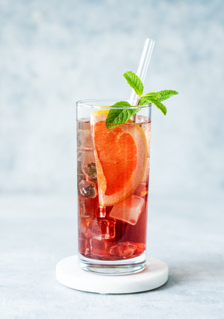 Refreshing cocktail with grapefruit, mint and ice in a glass on a blue background with natural light. Summer citrus drink or lemonade concept for cafe menu advertising banner. Front view, copy space.の写真素材