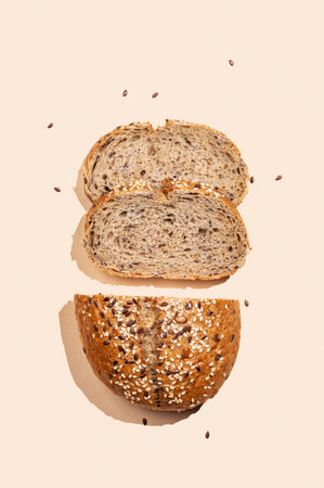 Freshly sliced multigrain bread with sesame and flax seeds on a bright beige background with shadow. Healthy food concept for advertising, store or bakery banner. Top view, copy space.の写真素材