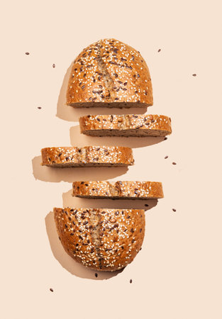 Freshly sliced multigrain bread with sesame and flax seeds on a bright beige background with shadow. Healthy food concept for advertising, store or bakery banner. Top view, copy space.の写真素材
