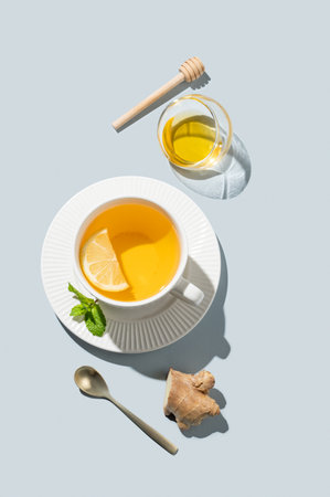 Hot tea with lemon, ginger, honey, and mint in a cup on a blue background with shadows. Concept of a drink to support immunity and health during the cold season. Advertising or banner menu cafe. Top view, copy space.の写真素材
