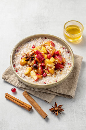 Overnight oatmeal with apple, cranberry and cinnamon in a plate on a light background with honey and spice. Concept for a healthy vegan meal for breakfast. Advertising menu or banner cafe. Top view, copy space.の写真素材