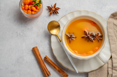 Sea buckthorn herbal tea in a cup on a light background with spices and berries. Concept for a hot autumn organic drink to boost immunity. Top view, copy space.の写真素材