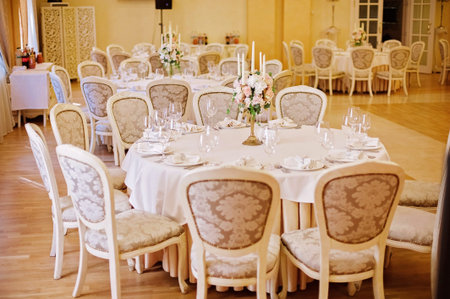 Guest tables with candlestick in rich decorated wedding banquet room