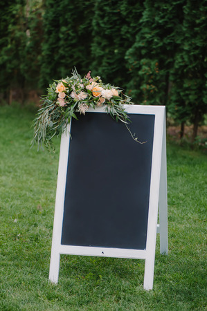 Chulk board, which stands on the grass for wedding inscription. Decorated with bouquetの写真素材