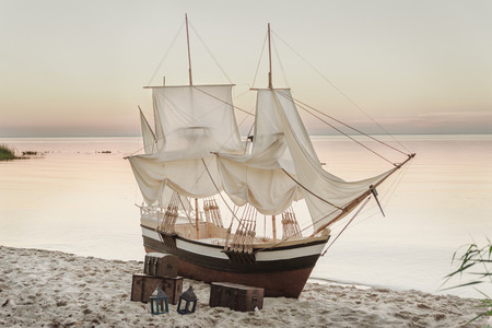 Wooden ship with white sails staying on the beachの写真素材