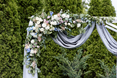 The stylish arch decorated with flowers and fabric. Elegant decoration of a ceremony of a weddingの写真素材
