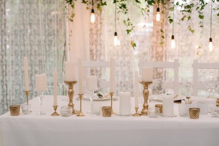 It is a lot of white candles in golden candlesticks of different height. Cozy details on a wedding tableの写真素材