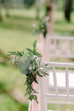 Wooden chairs at a wedding. The chairs for guests decorated with buttonholes and tapesの写真素材