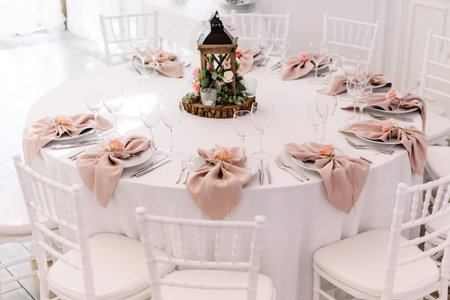 Wedding table service for reception of guests. Round table for the wedding lunch is decorated with...