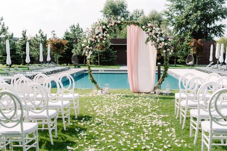 A stylish round green arch for a wedding ceremony on the lawn near the pool. Modern decoration of the place for the open-air marriage ceremonyの写真素材