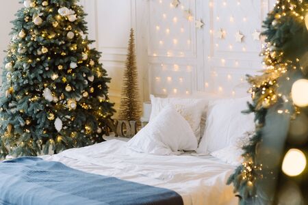 Stylish Christmas interior with a soft bed. Christmas tree with presents underneath in living roomの写真素材