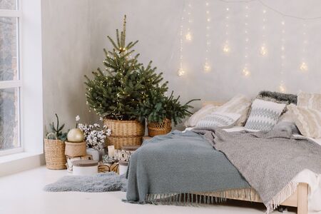 Christmas decorated bedroom interior with comfortable bed, Christmas fir tree and gift boxes on floor, copy space. Cozy home moment. Happy New Year. Christmas morningの写真素材