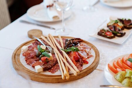 The original serving of Mediterranean delicacies on a thin sheet of lavash, on a round wooden board. Cheese, hamon, tomato and thin bread sticks. Beautiful food in the restaurantの写真素材
