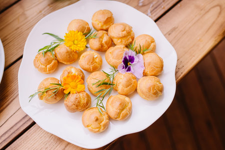 Small delicious eclers with golden crust. Delicious sweets on a white plate. Dish with baking...