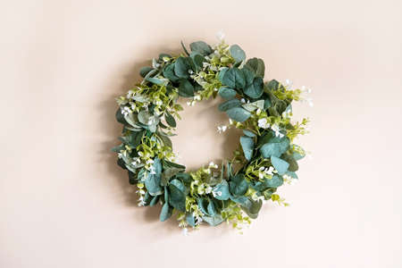 Decoration for Easter in the form of a wreath of eucaliptus branches on a beige wall. Holiday backgroundの写真素材