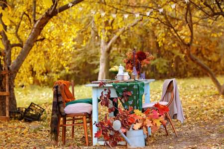Autumn themed holiday table setting arrangement for a seasonal party, cups, apples, candles, field...