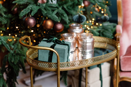Golden cart with present gift boxes near Christmas tree decorated with handmade eco paper balls.